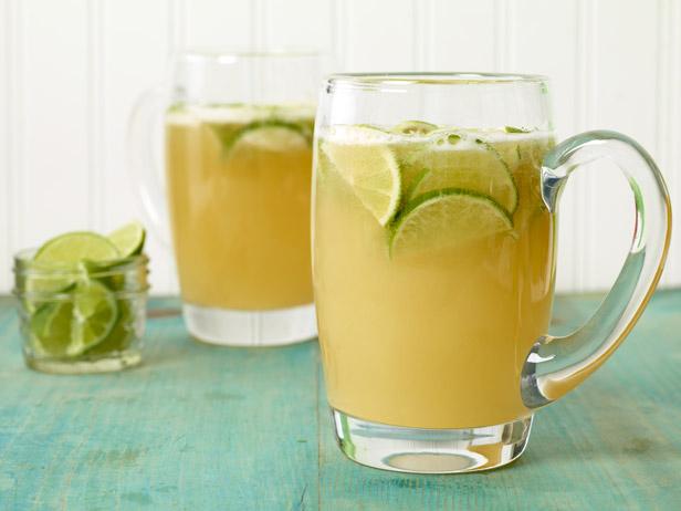 Lime beer cocktail garnished with lime wedges and served in a glass pitcher.