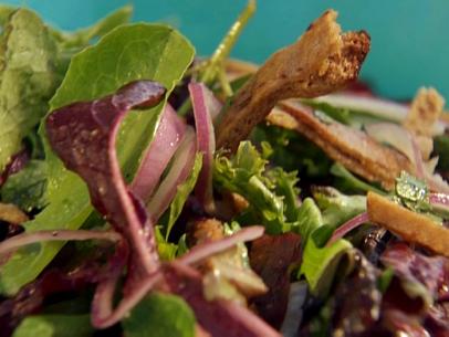 A Close-up of Mixed Greens with Red Onions and Pieces of Whole Wheat Pita