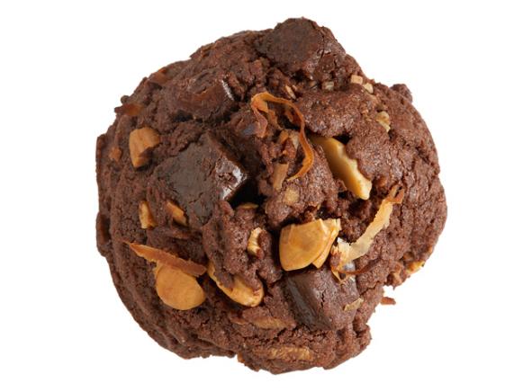 A chocolate cookie with nuts and chocolate chunks placed against a white background