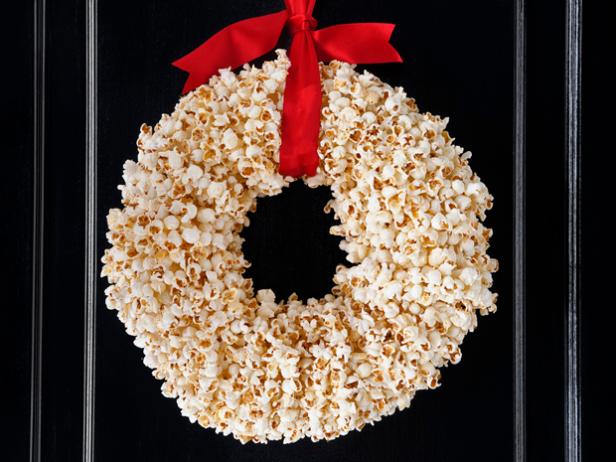 A Popcorn wreath hung with a red ribbon on a black door