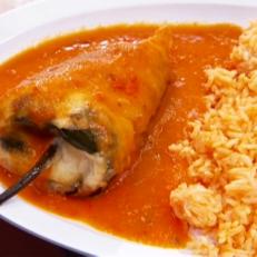 A Stuffed Pasilla Chile in tomato sauce beside a bed of rice