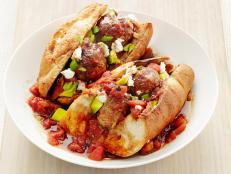 Two Meatball Subs Sitting in Tomatoe Sauce in a White Dish