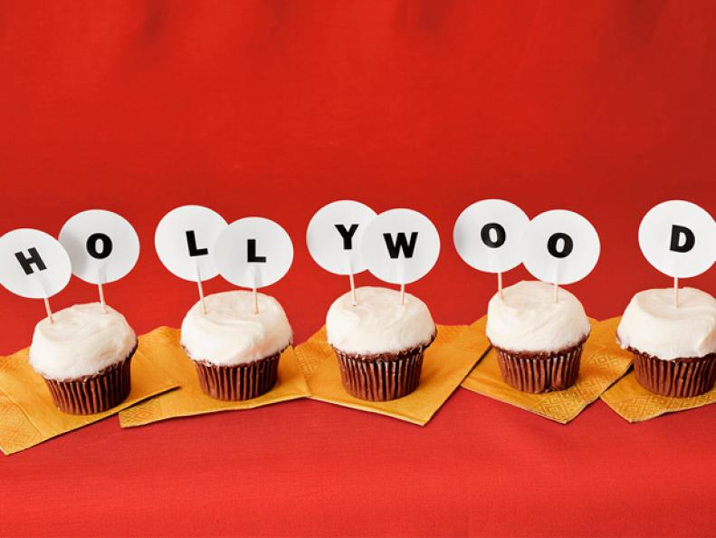 Five cupcakes with small letters on toothpics sticking out that spell Hollywood