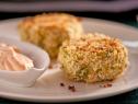 Two Crab Cakes along side a dish of spicy cream on a white plate