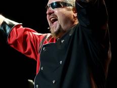 Guy Fieri on stage with hands raised and mouth wide open