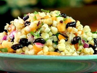 Grilled corn and bean salad with chopped yellow bell peppers, diced red onion, and cilantro leaves is served in a green bowl.