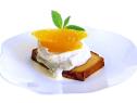 A slice of toasted pound cake that is topped with a scoop of ice cream, pieces of citrus fruit and mint