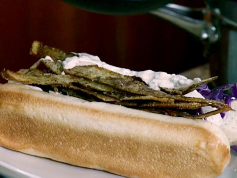 Bratwurst on a bun topped with crispy potatoes, braised cabbage, and cremolata.