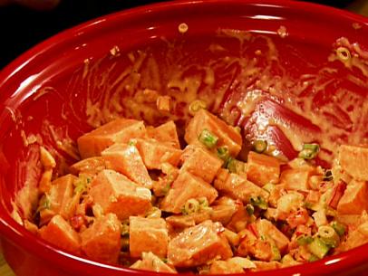 A sweet potato salad with onions in a red bowl