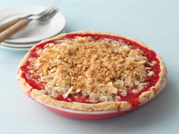 Rhubbard Strawberry Pie with a crunchy almond topping in a red and white dish alongside two forks on three stacked plates