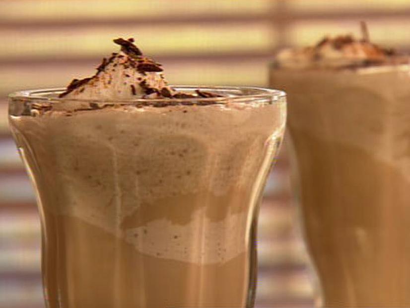 A coffee frappe topped with chocolate shavings in a tall slender glass