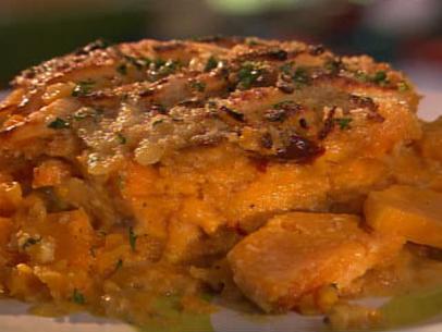 A close-up of yam gratin topped with herbs on a white and green dish