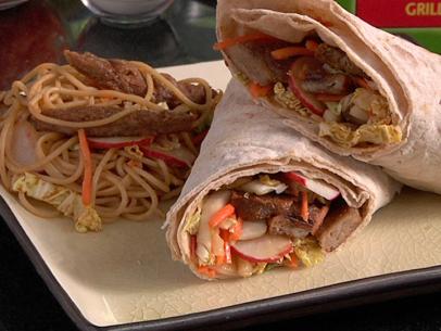 Two halves of a wrap beside a portion of the wrap ingredients on a small square cream colored plate