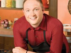 Next Food Network Star Finalist Paul Young smiling while wearing a red shirt and black apron
