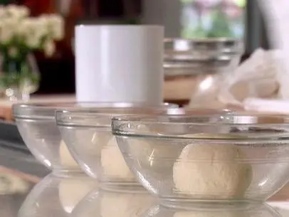 Three oiled glass bowls with equal sized balls of pizza dough in each. These balls of dough will rest for several more hours before they will be ready to use to make pizza.