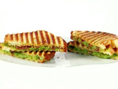 A close up of grilled cheese with spinach and pancetta sandwiches that have been cut in half diagonally.