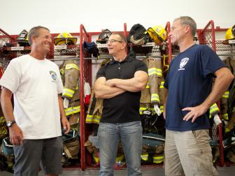 Host Robert Irvine, center, meets with firehouse Chief Wade Bradley, left, and President, Dan English, at the Ship Bottom volunteer fire department in Ship Bottom, New Jersey, as seen on Food Network's Restaurant: Impossible, Season 7.
