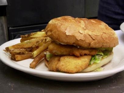 Cod sandwich on a bun with french fries.
