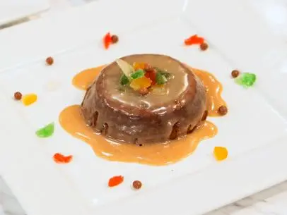 Final plated dish of Fruitcake Junkyard Brownie with a spiced orange liqueur and white chocolate glaze of the Great Holiday Cake-Over preheat challenge as seen on Food Network’s Holiday Baking Championship,
Season 1