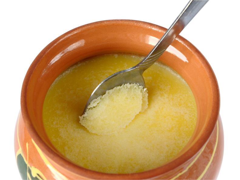 Melted butter in a clay pot on a white background