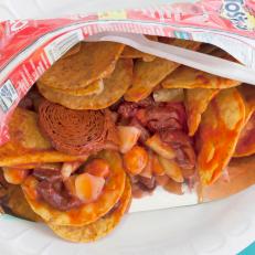 Tostilocos are a street snack with a cultlike following. A small bag of Tostitos is ripped open lengthwise, then dressed with chamoy (a sauce made of pickled fruit and chili), cucumber, peanuts, tamarindo candies, salsa, lime and Clamato.
