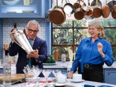 Host Geoffrey Zakarian shakes a large carafe as guest Martha Stewart demonstrates her Martini cocktail as seen on Food Network's The Kitchen, Season 7.