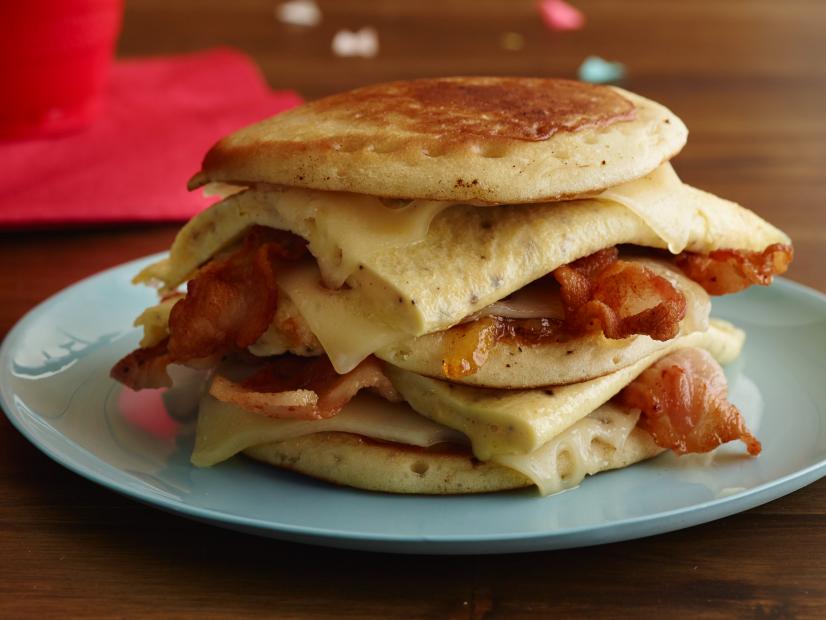 FNK HANGOVER BACON, EGG, AND CHEESE PANCAKE SANDWICH Food Network Kitchen Food Network Bacon, Pancakes, Orange Marmalade or Apricot Preserves, Swiss Cheese, Eggs, Unsalted Butter