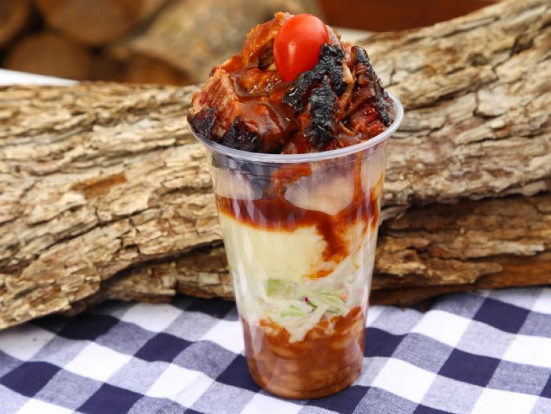 This deceptive looking sundae is actually a savory treat made with slow smoked BBQ beef and pork, layered with coleslaw, beans, mashed potatoes, and burnt brisket ends all smothered in special BBQ sauce, as seen on Food Network's Carnival Cravings with Anthony Anderson.