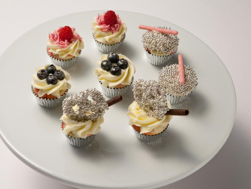 Host Lorraine Pascale's mini wedding cupcakes.  Lorraine made mini vanilla cupcakes with a vanilla frosting and topped them off with assorted blueberry's, rasberry's, silver candy beads, and pretzels, as seen on Food Network's Worst Bakers In America, Season 1.