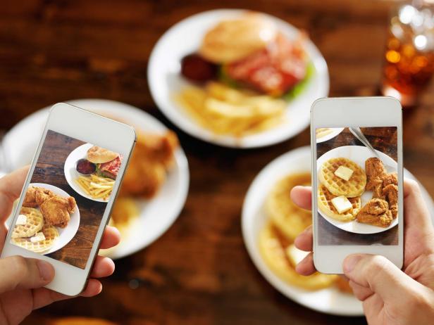 two friends taking photo of their food with smartphones