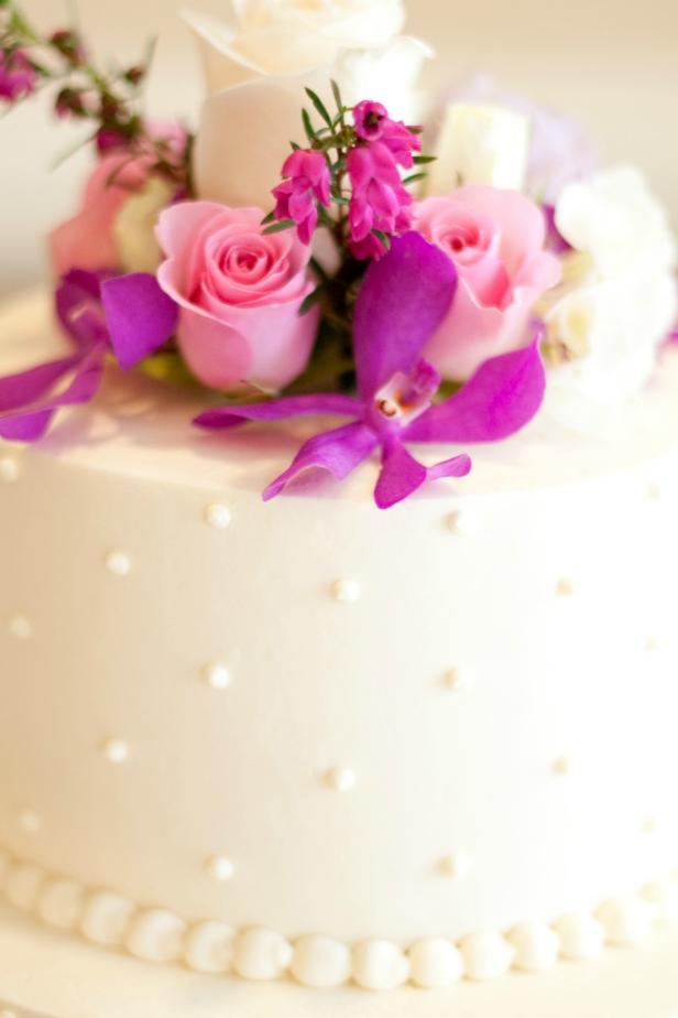 Tiered layered white wedding cake with pink and white roses and purple orchids. Converted from 14-bit RAW file.