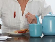 Woman dropping jam down her blouse at breakfast