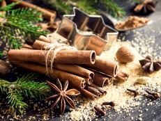 Christmas spices and baking ingredients on dark wooden background. Cinnamon, anise stars, nutmeg, cardamom, cloves, brown sugar and cocoa powder for Christmas cake, cookies.