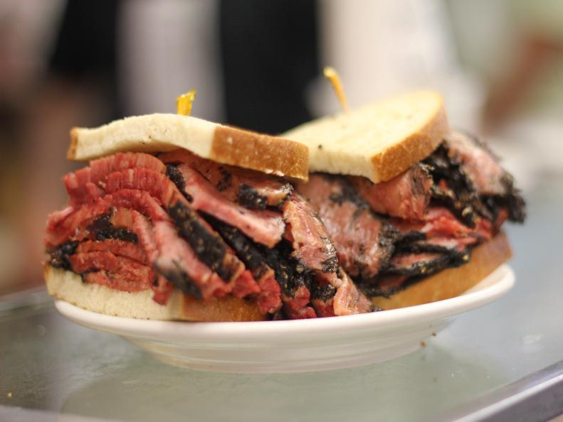 Pastrami is made by curing meat with salt and spice, then smoking and steaming it until tender. It was brought to NYC by Romanian Jews in the late 1800s, during a period of mass Eastern European immigration. Many of those newcomers opened kosher delis and somewhere along the way, the combination of hot, sliced beef pastrami and spicy brown mustard on lightly seeded rye bread was born. Although hundreds of Jewish delicatessens opened in the late 19th and early 20th centuries, one of the oldest remaining is Katz’s Deli on the Lower East Side. Opened in 1888, the cash-only cafeteria-style icon is a local and tourist favorite for its towering hand-cut hot pastrami sandwiches, sliced by gruff cutters, many of whom live in the neighborhood. It’s as classic a New York City experience as one can find.