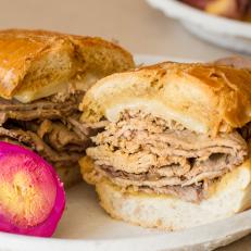 When a sandwich is so revered, it's not uncommon for a few people to lay claim to it. Such is the case with the invention of the French dip sandwich, fought over by Philippe The Original and Cole's, both in Los Angeles. However, most Angelenos believe that Philippe's story edges out Cole's, especially because Philippe's has served the iconic sandwich for nearly a century. Founded in 1908 by Philippe Mathieu, the restaurant ascribes the French dip discovery to pure accident when, in 1918, Mathieu inadvertently dropped a French roll into the roasting pan filled with beef au jus. A police officer happily gobbled down the sandwich despite the soaked bread and returned the next day with his pals, requesting the "dipped" sandwich once again. It landed on the menu helped make Philippe's a treasured culinary destination.