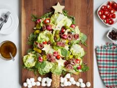 This cheery holiday salad is a fun (and delicious!) decorating idea for a party. A trio of lettuces create the evergreen tree, and items from the deli counter and salad bar become an edible garland.