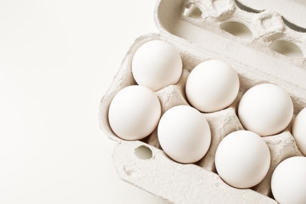 White eggs in carton on a table.
