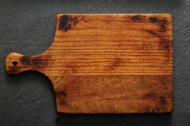 A rustic wood cutting board on a black slate stone with nothing on it, left blank for copy space.  Please see my portfolio for other food and drink images. 