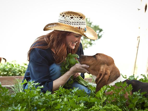 Host Ree Drummond picks herbs in her garden with the help of Walter the Bassett Hound, as seen on Food Network's Pioneer Woman Season 1.