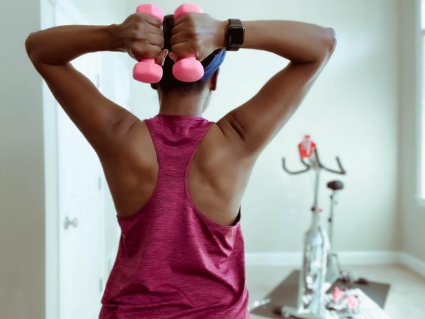 Mid adult black woman enjoys light upper body workout before at-home cycling session