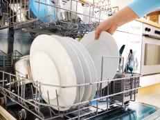 close-up of female hands loading dishes to the dishwasher