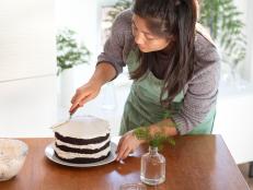 Eurasian millennial woman making vegan layered chocolate cake with vanilla icing at home.  Vancouver, British Columbia, Canada.