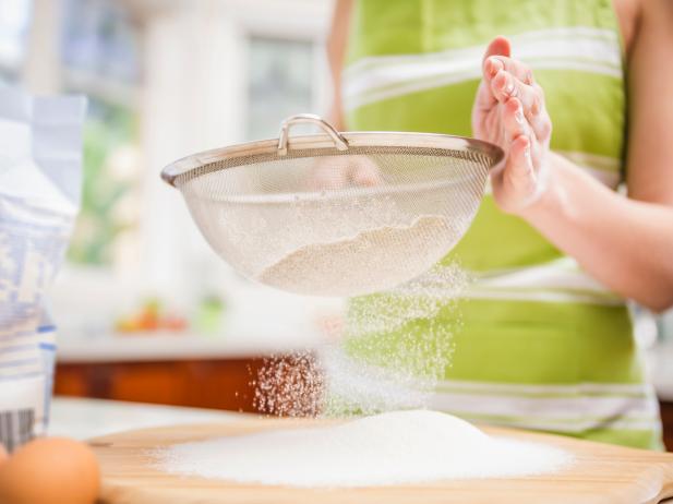 Hispanic woman sifting flour in domestic kitchen