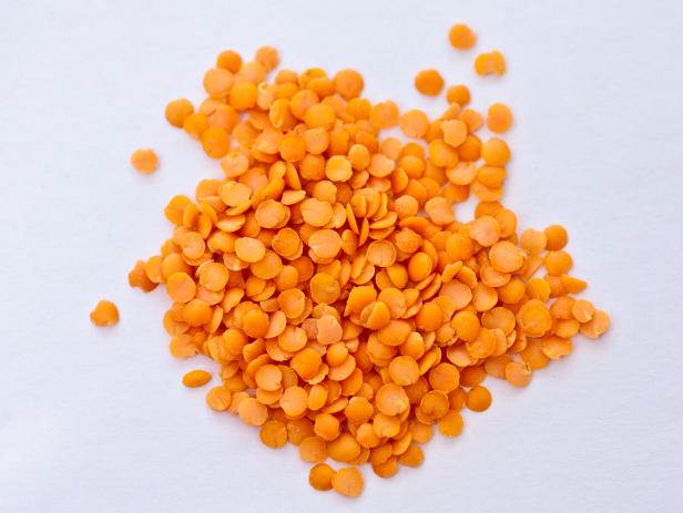 Close-up of red lentils on a white background.