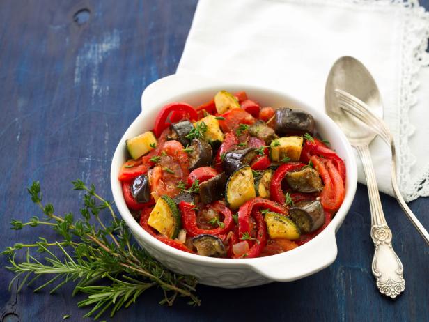Ratatouille, a traditional French dish of fresh vegetables in a white ceramic bowl on a dark blue background