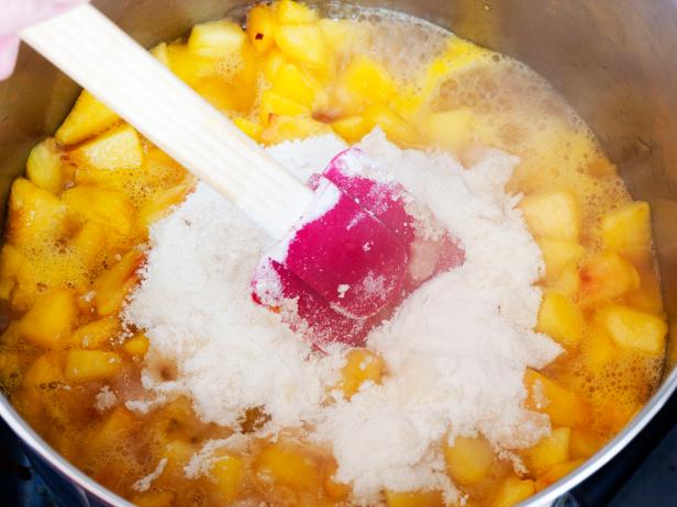 "Stirring cut-up peaches, pectin and sugar in a pan while heating to make jam.All images in this series..."