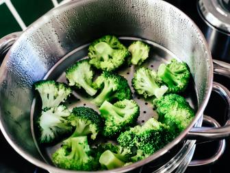 Broccoli florets being cooked in a steamer.