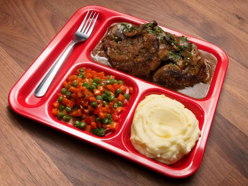Anne Burrell’s Salisbury Steak with Garlic Mashed Potatoes, Peas, Carrots and Peppers is displayed, as seen on Worst Cooks in America, Season 23.
