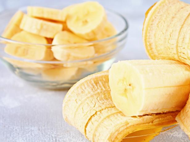 Bananas are whole and cut on a slice in a cup on a gray background