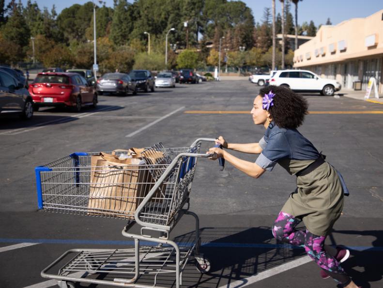 Chef Gabrielle running back to her station with a cart of groceries, as seen on Supermarket Stakeout, Season 3.
